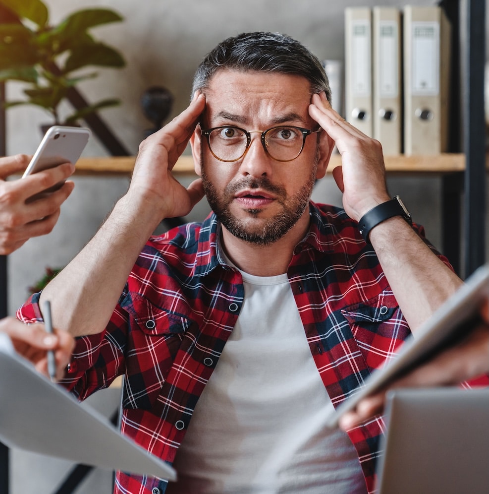 Overworked businessman sitting at laptop overloaded with work multiple tasks in modern office Overworked businessman sitting at laptop overloaded with work multiple tasks in modern office